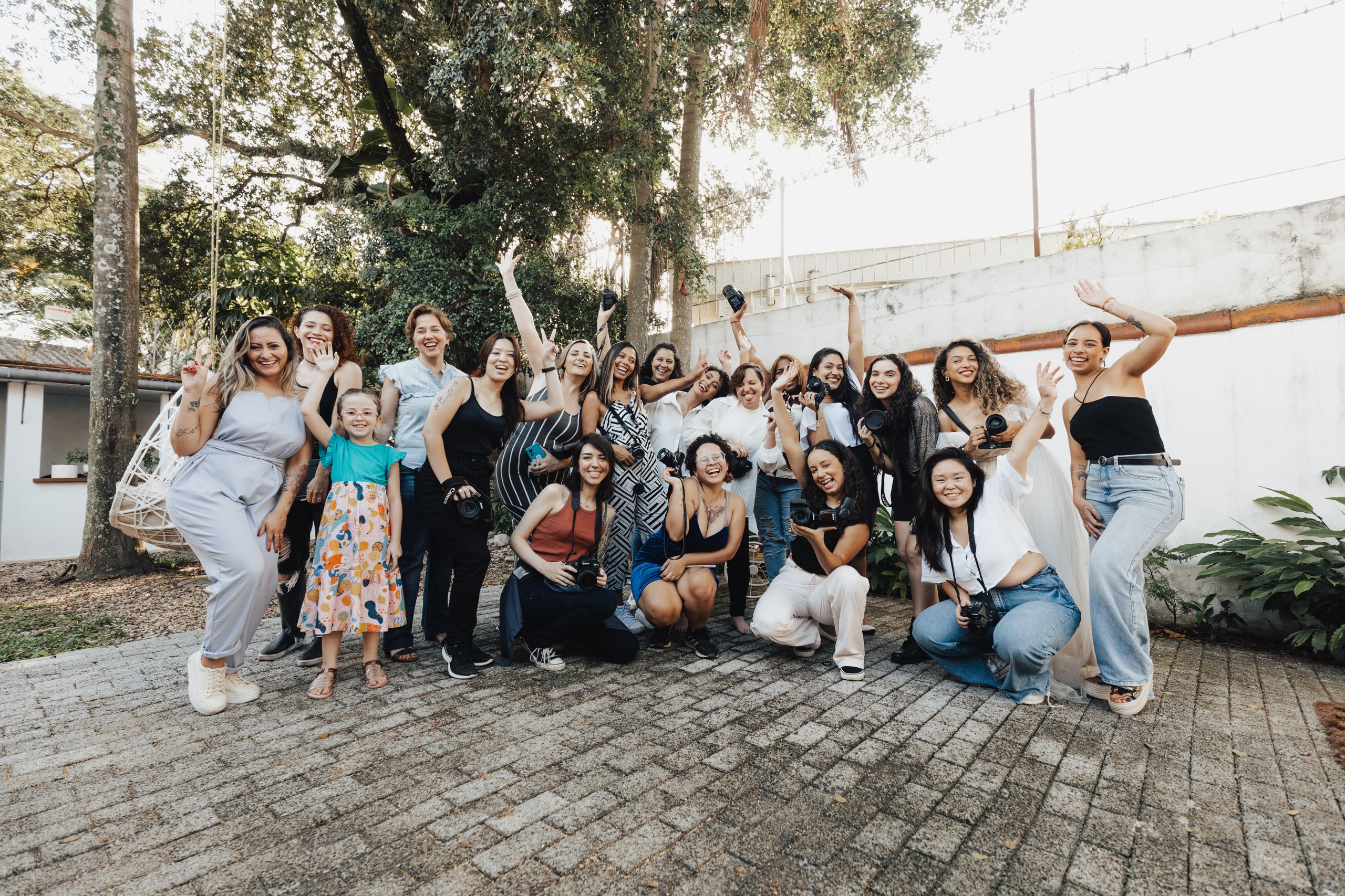 A joyful group of diverse women photographers posing and celebrating outdoors.