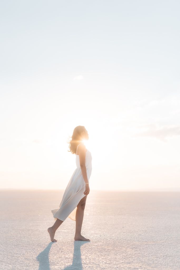 A serene scene of a woman walking barefoot on a salt lake during sunrise in Göreme, Türkiye.