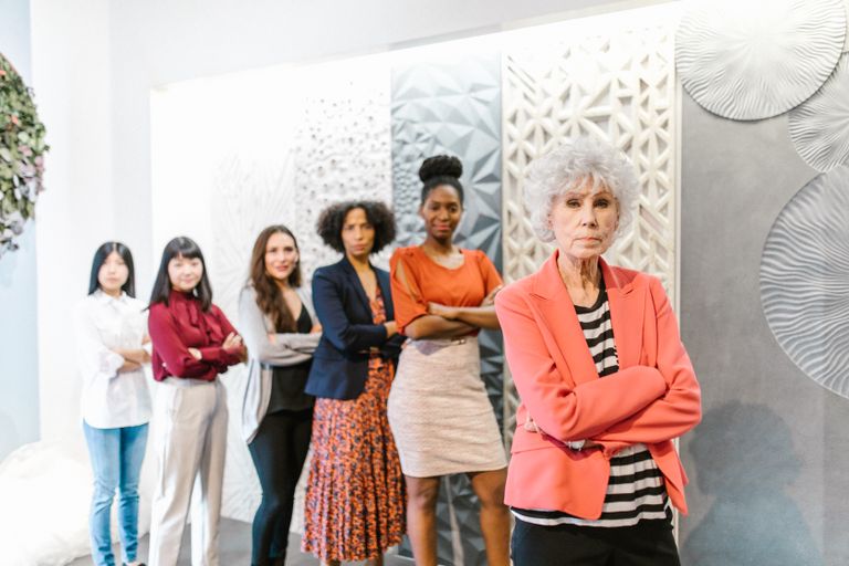 A diverse group of business women standing together in a modern office setting displaying leadership and confidence.