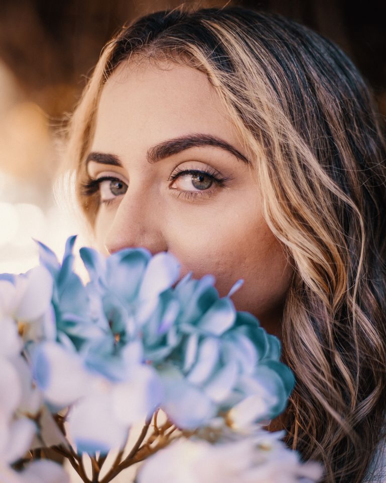 Elegant woman with blue hydrangeas, capturing summer beauty.