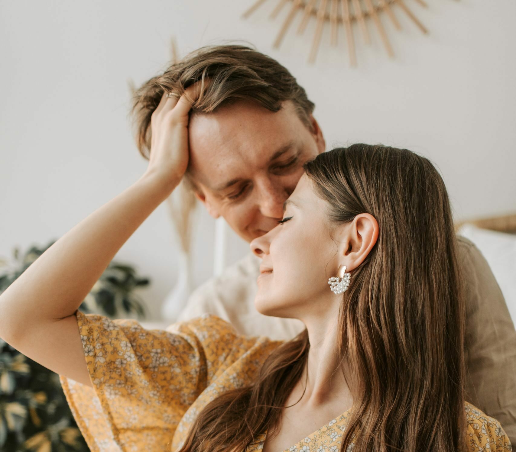 Tender moment with couple sharing an affectionate embrace, indoors, in warm tones.